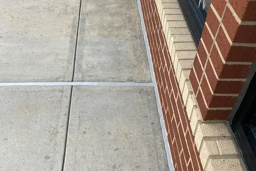 sealed concrete joint against brick wall of building
